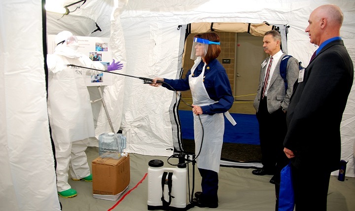 Defense Health Agency program analyst Brian Smith (right), and chief of Reserve and Service Member Support Services Jody Donehoo (center), watch a decontamination demonstration at the Air Force Medical Service and U.S. Public Health Services Ebola Response Partners exhibit during Federal Health 2015 in San Antonio. 