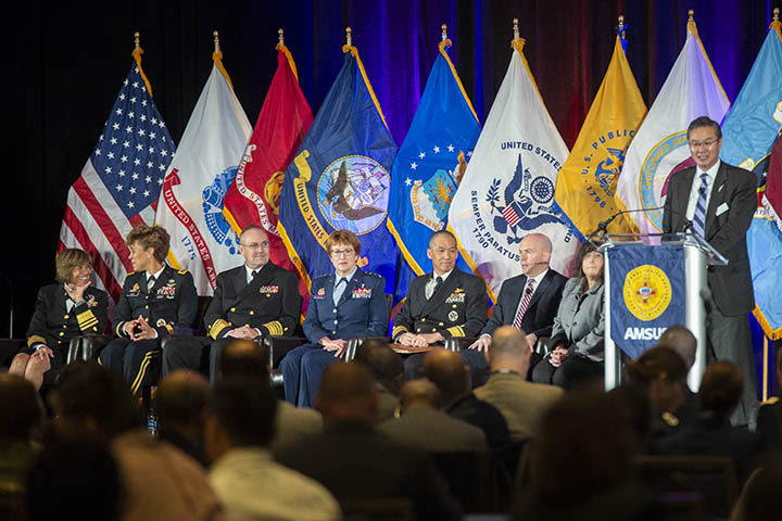 Dr. John Cho (far right), AMSUS executive director, introduces speakers (from left) Navy Vice Adm. Raquel Bono, Defense Health Agency director; Lt. Gen. Nadja West, Army surgeon general; Vice Adm. Forrest Faison III, Navy surgeon general; Lt. Gen. Dorothy Hogg,  Air Force surgeon general; Navy Rear Adm. Colin Chinn, Joint Staff surgeon, Dr. Richard Thomas, president of Uniformed Services University of the Health Sciences; and Dr. Terry Adirim, deputy assistant secretary of defense for health services policy and oversight.  