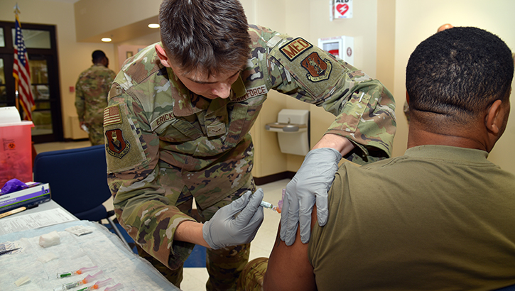 military personnel administers vaccine