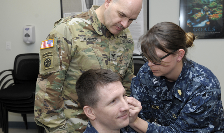 Army Col. Dean Hommer (left), a visiting instructor from Brooke Army Medical Center at Fort Sam Houston, Texas, observes as Navy nurse Lt. Rachael Wheelous (right) practices the battlefield acupuncture technique on Navy nurse Lt. Brent Pavell (center) during training at Naval Health Clinic Corpus Christi, Texas. (U.S. Navy photo by William Love) 