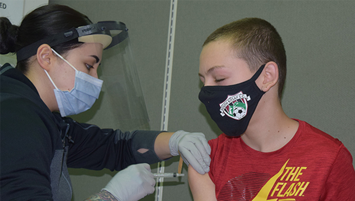 Image of Son of military personnel receiving his COVID-19 vaccine.