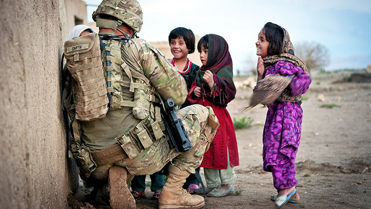 U.S. Army Sgt. Jason Smith, a paratrooper with the 82nd Airborne Division’s 1st Brigade Combat Team, talks with a group of Afghan children during an Afghan-led clearing operation on April 28, 2012, in the Ghazni province of Afghanistan. (Photo by U.S. Army Sgt. Michael J. MacLeod)