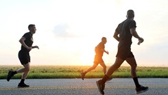 Three soldiers running on blacktop road in the country