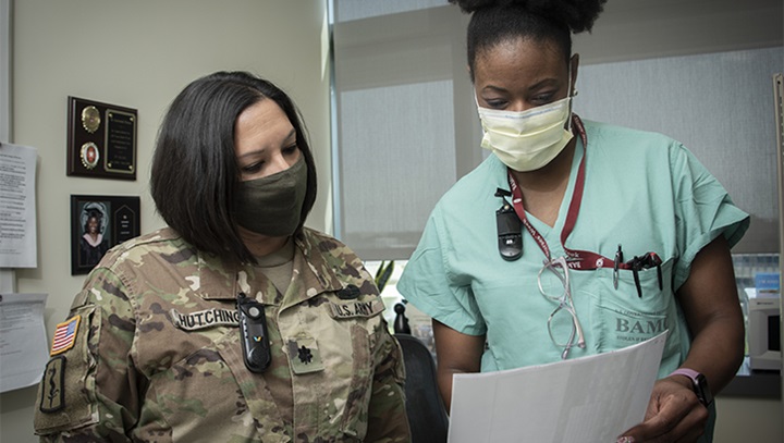 Image of Military health personnel wearing face mask reviewing a patient's record.