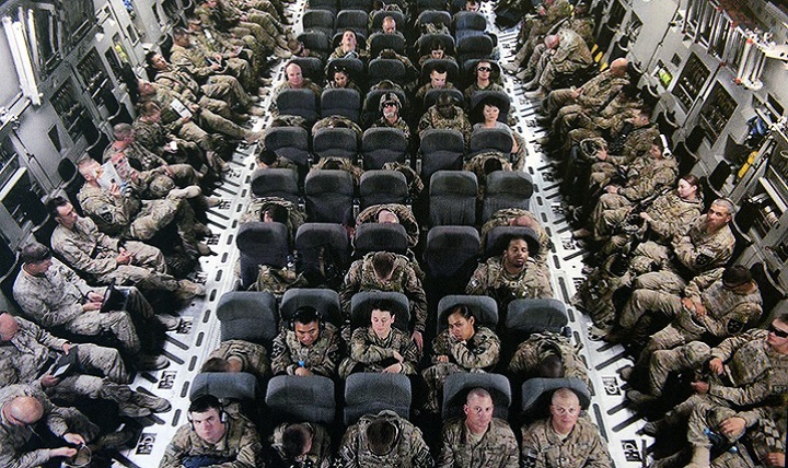 Soldiers try and get comfortable and get some sleep on their way home from deployment. 