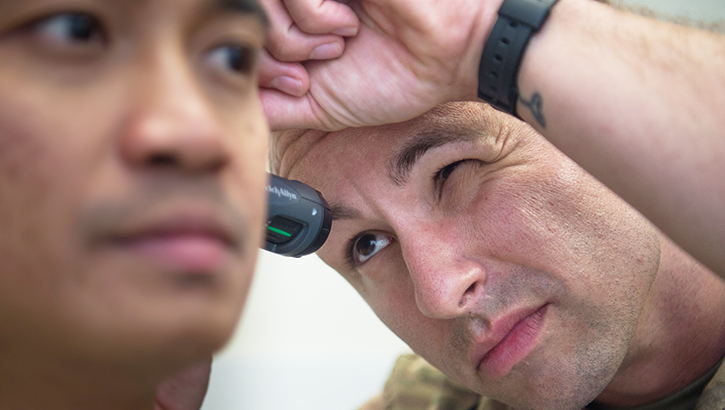 A doctor looking into a soldier's ear