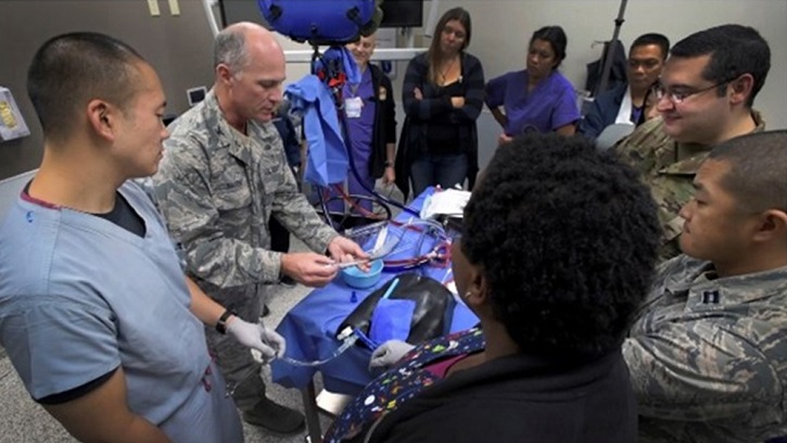 Image of Military personnel sitting around a table, exhibiting medical items. Click to open a larger version of the image.