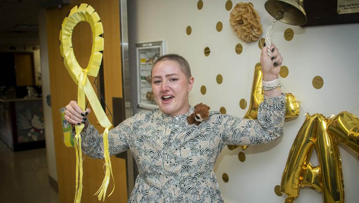 Military personnel rings the bell signaling the end of her cancer treatment