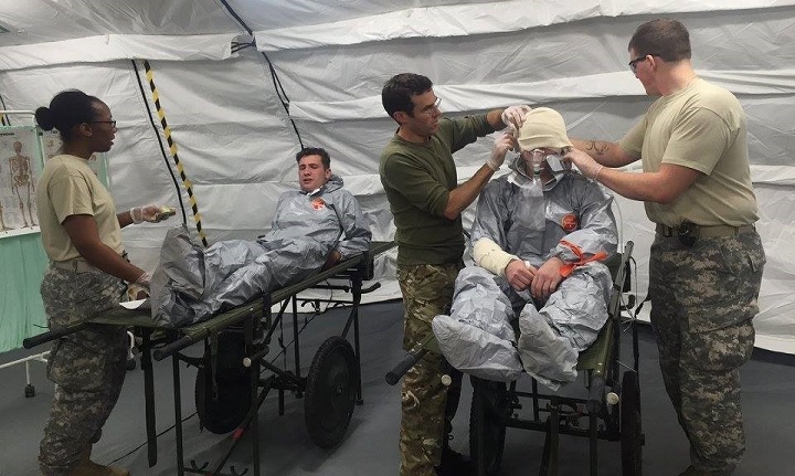 Army Capt. Keisha Green (left) and Pfc. Christopher Stapleton (right) assist with triaging and caring for casualties in a CBRN environment with the U.K.'s 33 Field Hospital at Bordon Training Area for Exercise Jorvik Look 2015. Army medics integrated and trained with the U.K. hospital, learning the capabilities of a NATO Role II hospital while building capacity and interoperability with European allies. (U.S. Army photo by Capt. Sandy Said)