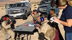 Military personnel sitting at a table collecting data