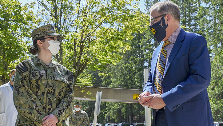 Man in mask presents military coin to female soldier