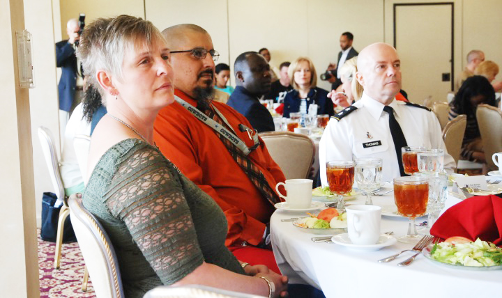 Donna and Adam Porras, along with Army Maj. Gen. Richard Thomas, director of the Defense Health Agency Healthcare Operations directorate, attend the Caregiver Recognition Luncheon at Fort Belvoir, Virginia, May 7, 2015. Donna was one of about 20 caregivers honored during the event for their support of their wounded warrior spouses.