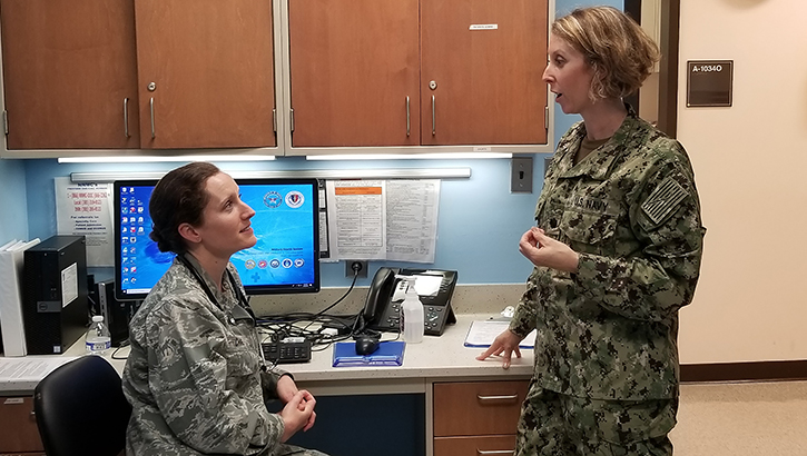 Navy Cmdr. Francesca Cimino, M.D. (standing) confers with a colleague in the Family Medicine department at Uniformed Services University of the Health Sciences in Bethesda, Maryland. (Courtesy photo)