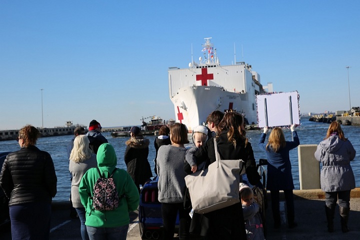 Family and friends of crew members aboard Military Sealift Command’s hospital ship USNS Comfort wait as the ship pulls into Naval Station Norfolk, Dec. 18. Comfort returned to Virginia after completing its 11-week medical support mission to South and Central America, part of U.S. Southern Command’s Operation Enduring Promise initiative. (U.S. Navy photograph by Brian Suriani)