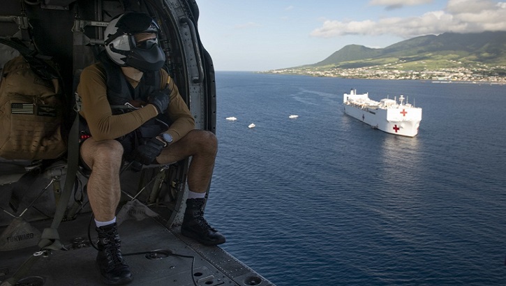 Navy Naval Aircrewman (Helicopter) 2nd Class Benjamin Lazarus flies in an MH-60S Seahawk assigned to the “Dragon Whales” of Helicopter Sea Combat Squadron 28, as it transports supplies from the hospital ship USNS Comfort for a temporary medical treatment site in Basseterre, St. Kitts and Nevis. (U.S. Navy photo by Mass Communication Specialist 2nd Class Morgan K. Nall)