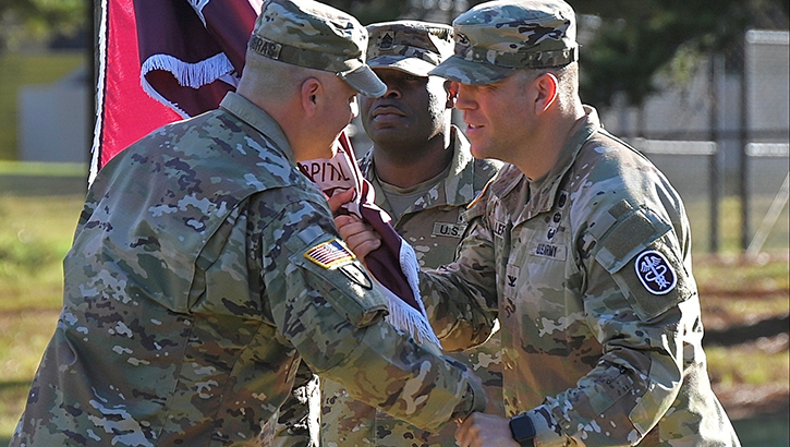 Col. Patrick Miller, commander of Bayne-Jones Army Community Hospital, passes the unit guidon to Command Sgt. Maj. Victor M. Contreras Jr. during the change of responsibility ceremony