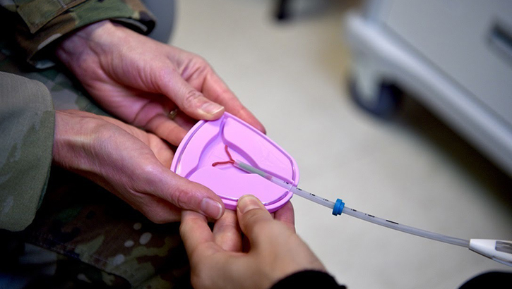 Image of military medical personnel demonstrates an intrauterine device.