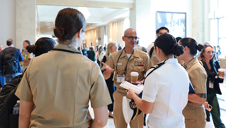 Image of Defense Health Network Pacific Rim Director Rear Adm. Guido Valdes talks with a group of residents from Naval Medical Center San Diego at the 2024 Military Health System Research Symposium in Kissimmee, Fla. Valdes, who is also the Naval Medical Forces Pacific commander, was at the event to support presenters from military treatment facilities within his Network as well as those from Navy Medicine’s eight medical research laboratories which fall under his purview. (Department of Defense photo by Regena Kowitz/Released).