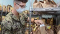 Military personnel wearing a face mask handling prescription refills at a pharmacy