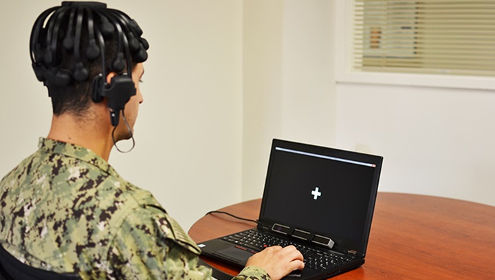 Image of Soldier sitting in front of a laptop with headphones on.