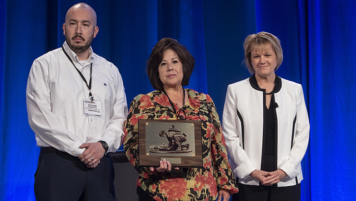 Steven Rodriquez (left), and wife, Christine Rodriquez (center), accept a posthumous award for Dario Rodriguez from Seileen Mullen, the acting Secretary of Defense for Health Affairs. 