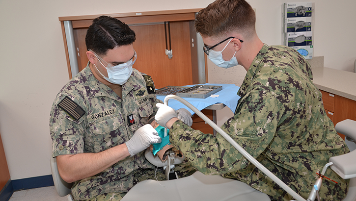 U.S. Navy Petty Officer Petty Officer 1st Class Caleb Gonzalez, left, an instructor in the Navy dental assistant program at the Medical Education and Training Campus, Joint Base San Antonio-Fort Sam Houston, in Texas, acts as a dentist while training a student in the dental assisting lab. Gonzalez, an instructor in the program, will realize a childhood dream when he begins dental school this summer. (Photo by Lisa Braun, Medical Education & Training Campus)