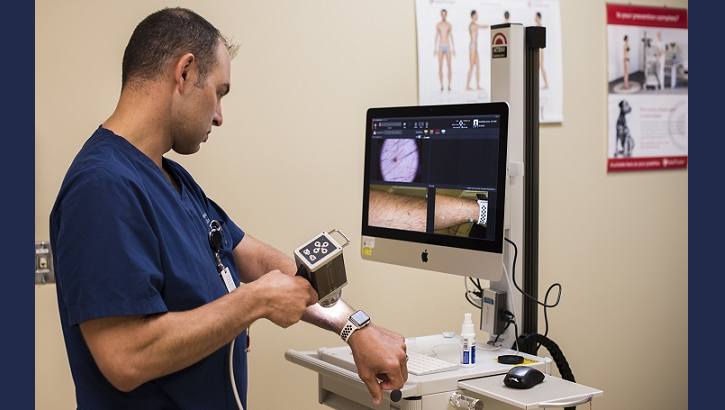 Air Force Maj. Thomas Beachkofsky, 6th Health Care Operations Squadron dermatologist, uses a body scanner microscope to take a picture of a spot on his arm at MacDill Air Force Base, Florida. A new software upgrade allows a complex algorithm to analyze an image captured with a camera and rate the severity of the spot for a dermatologist to review. (U.S. Air Force photo by Senior Airman Adam R. Shanks)