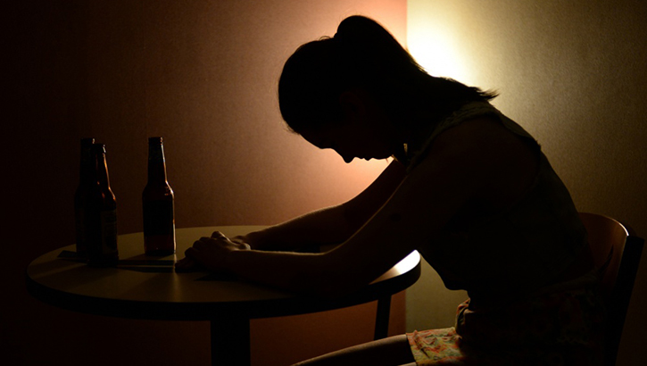 Image of Shadowed image of person sitting at a desk with their head down. Click to open a larger version of the image.