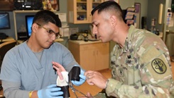 Staff Sgt. Francisco Mendez, right, the noncommissioned officer in charge of the EACH Orthopedics Department, teaches Pvt. William Viera, a 68w combat medic, how to put a cast on a patient's arm.