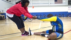 Woman on left stretching her husband's left arm and right leg