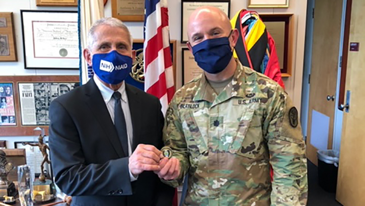 Image of Two men in masks; one a military soldier, and the other wearing a suit.