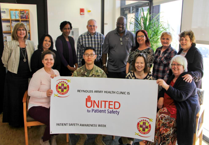 A dozen members of the Reynolds Army Health Clinic at Fort Sill, Okla. stand behind a “United for Patient Safety” banner.