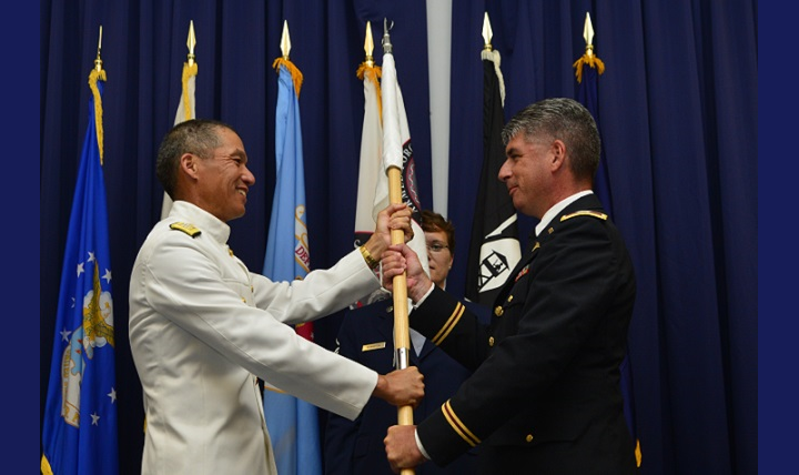 Army Col. Louis Finelli (right) receives the Armed Forces Medical Examiner System guidon from Navy Rear Adm. Colin Chinn, Defense Health Agency director of research, development and acquisition, during a Change of Directorship Ceremony July 18, 2016, at the Landings on Dover Air Force Base, Delaware. (U.S. Air Force photo by Senior Airman William Johnson)