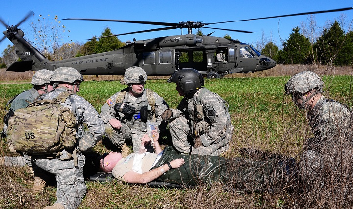 Flight Medic Army Staff Sgt. Jeremy Lowe, Detachment 1, HHD, 2/238 Aviation Regiment, consults with a medical team as they prepare to load a simulated casualty aboard a UH-60 Black Hawk medevac helicopter for transportation to a field hospital. 