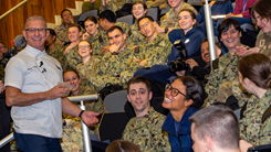 Chef Robert Irvine engages with smiling medical students at the Uniformed Services University while demonstrating healthy cooking and food preparation