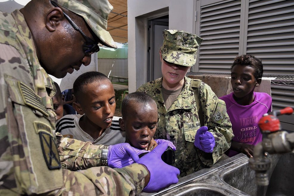 Army Maj. Donald Dais (left), 443rd Civil Affairs Battalion Functional Specialty Team Environmental Health officer in charge, and Navy Petty Officer 1st Class Samantha Ward, (center) assigned to the Camp Lemonnier Emergency Medical Facility, test water samples at Caritas Djibouti, a mission serving humanitarian aid and education to Djiboutian children living on the streets. The team checked for chlorine levels and retrieved samples to test for bacteria, in addition to conducting a food handling and sanitation tutorial. (U.S. Air Force photo by Tech. Sgt. Andria Allmond)