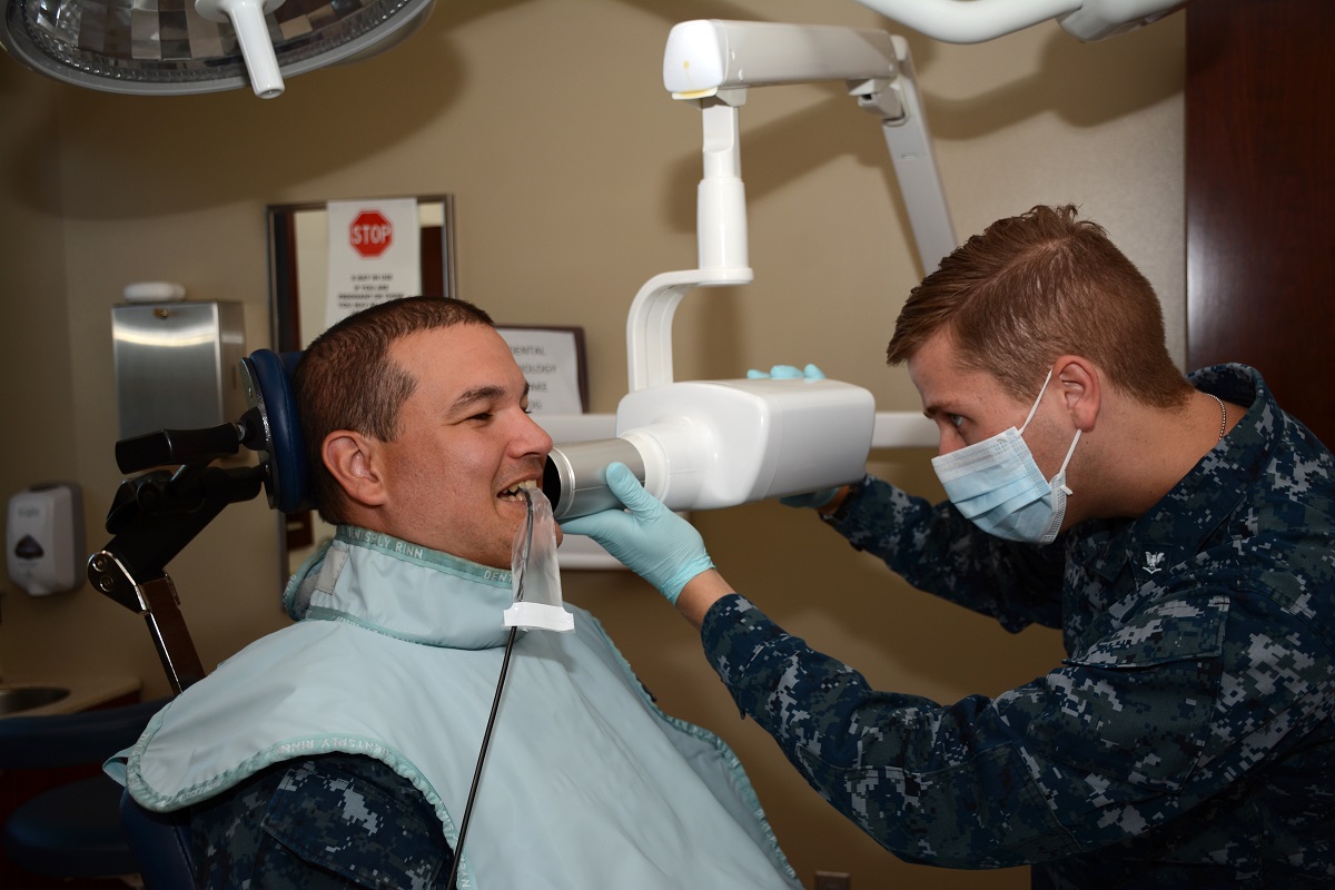 Navy Dental Assistant Petty Officer 3rd Class Donald Kern positions the digital X-Ray tubehead, or camera, next to his patient’s jaw for bitewing X-rays as part of an annual dental exam at Tinker Air Force Base. (U.S. Air Force photo/Staff Sgt. Lauren Gleason)
