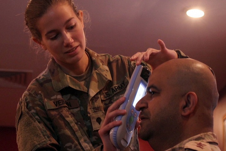 Army Spc. Anne Veiman, 452d Combat Support Hospital, demonstrates the capabilities of the InfraScanner handheld TBI detector on Kuwaiti army Col. Raed Altajalli, assistant director of Kuwait North Military Medical Complex in Al Jahra, Kuwait City, Kuwait. (U.S. Army photo by Sgt. Connie Jones)