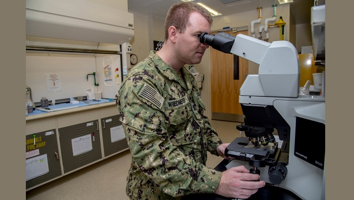 Navy Petty Officer 2nd Class Tyler Wiedmeyer, Armed Forces Medical Examiner System histotechnichian, looks at slides of tissues under a microscope before handing them off to a medical examiner June 6, 2019. The stained tissues help medical examiners see down to the cellular level for a diagnosis of cause of death. (U.S. Air Force photo by Staff Sgt. Nicole Leidholm) 