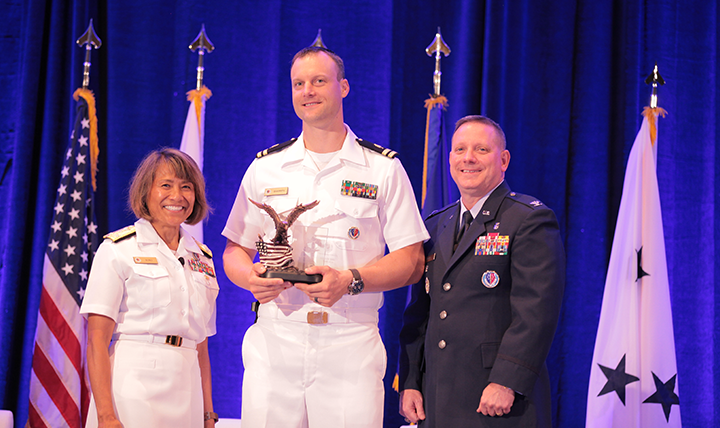 Vice Admiral Raquel C. Bono, director of the Defense Health Agency, presents the DHA/J-6 Company Grade Officer of the Year Award to Lieutenant Adam Sharrits at the Defense Health Information Technology Symposium on July 25, 2017 in Orlando, Florida.