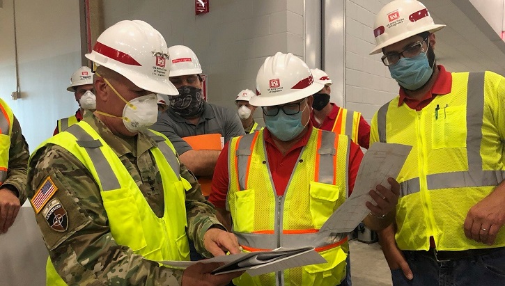 Image of three men in construction gear standing around plans