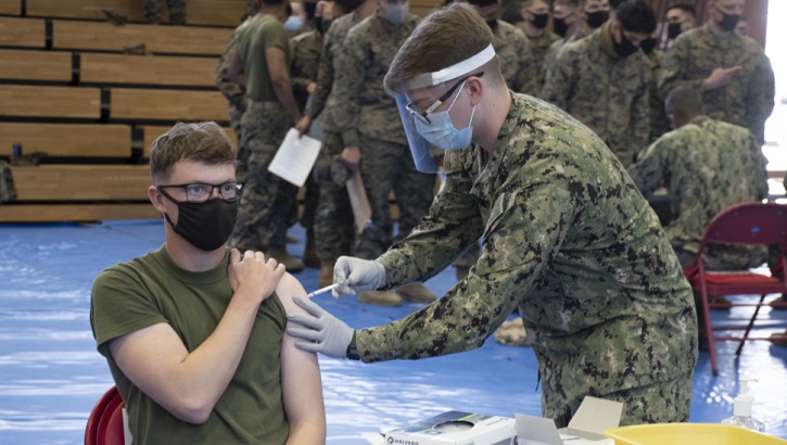 Image of Military personnel wearing a face mask and a face shield administering the COVID-19 vaccine. Click to open a larger version of the image.