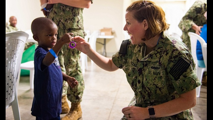 Navy Cmdr. Sara Naczas, a nurse assigned to the hospital ship USNS Comfort, helps a boy roll his yo-yo at a temporary medical treatment site in Kingston, Jamaica. Comfort is working with health and government partners in Central America, South America, and the Caribbean to provide care on the ship and at a temporary medical treatment site, helping to relieve pressure on national medical systems, including those strained by an increase in cross-border migrants. (U.S. Navy Photo by Mass Communication Specialist 3rd Class Maria G. Llanos)