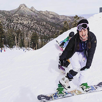 Woman snowboarding with a brace on her knee