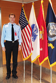 Image of man standing next to four flags
