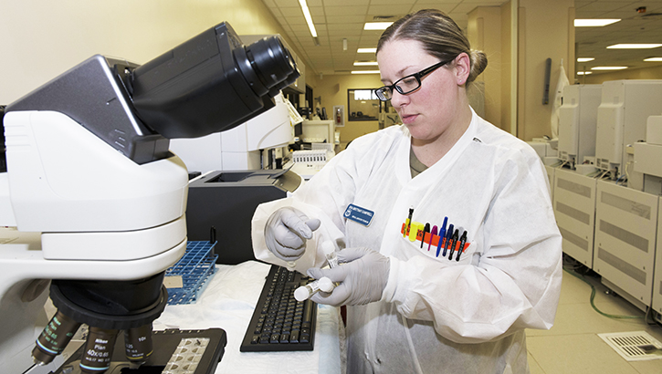 Image of woman in lab coat looking at samples in test tubes