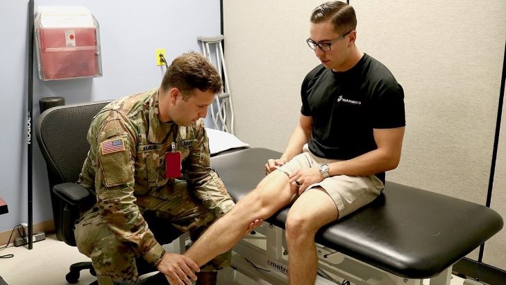 Image of Military health personnel checking out an injury. Click to open a larger version of the image.