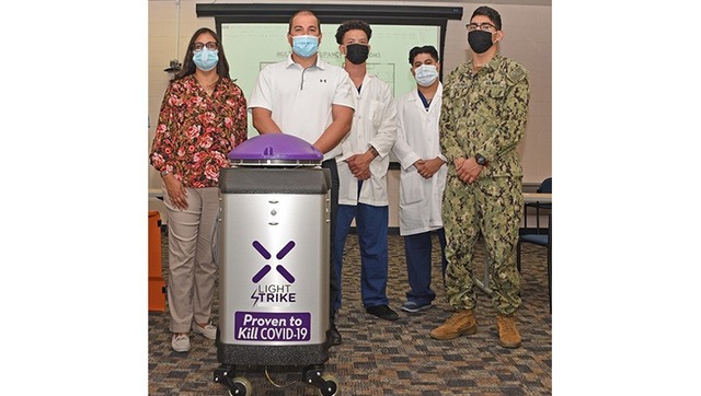 Image of Hospital personnel standing with a cleaning robot.