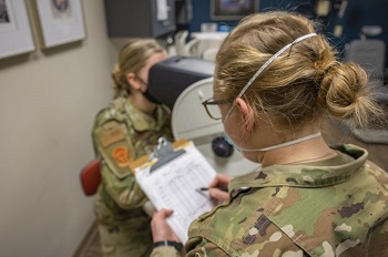 Military personnel wearing a mask performing an eye exam