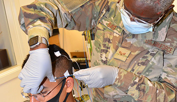 Military health personnel wearing face mask practicing EEG
